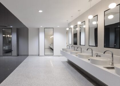 Compact commercial bathroom with floating vanity and frameless partitions.